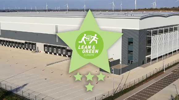 Large warehouse with loading docks and wind turbines in the background, overlaid with a green Lean & Green Europe star logo and four stars beneath it.