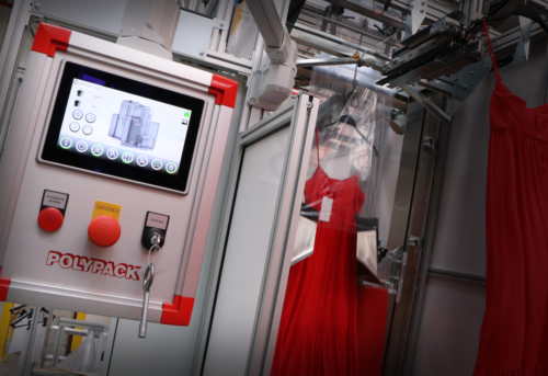 A red dress is being packaged by automated machinery. A control panel with buttons and a display is visible on the left.
