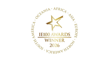 Gold star emblem with “IE100 Awards Winner 2026” in the center, surrounded by the continents' names in a circle on a white background.