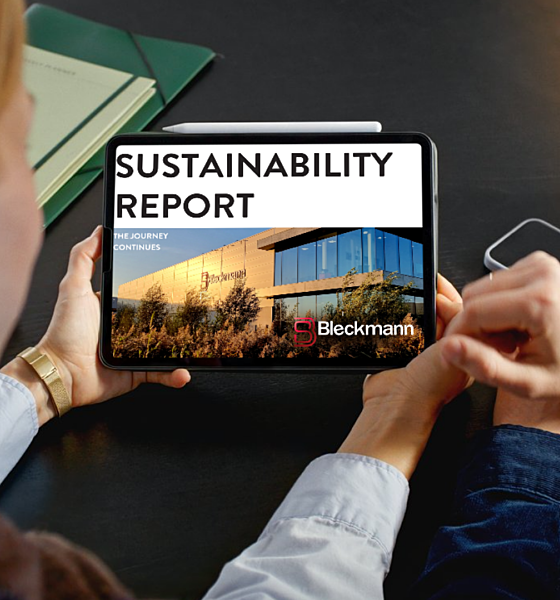Two people sit at a table looking at a tablet displaying a sustainability report with the Bleckmann logo and an image of a building.