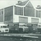 Vintage black and white photograph showcasing a row of parked trucks in front of a commercial building.