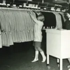 Two women browsing clothing racks in a well-lit boutique, examining stylish garments.