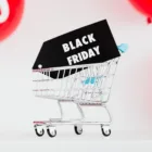 A shopping cart filled with Black Friday deals, adorned with vibrant red balloons for a festive touch.