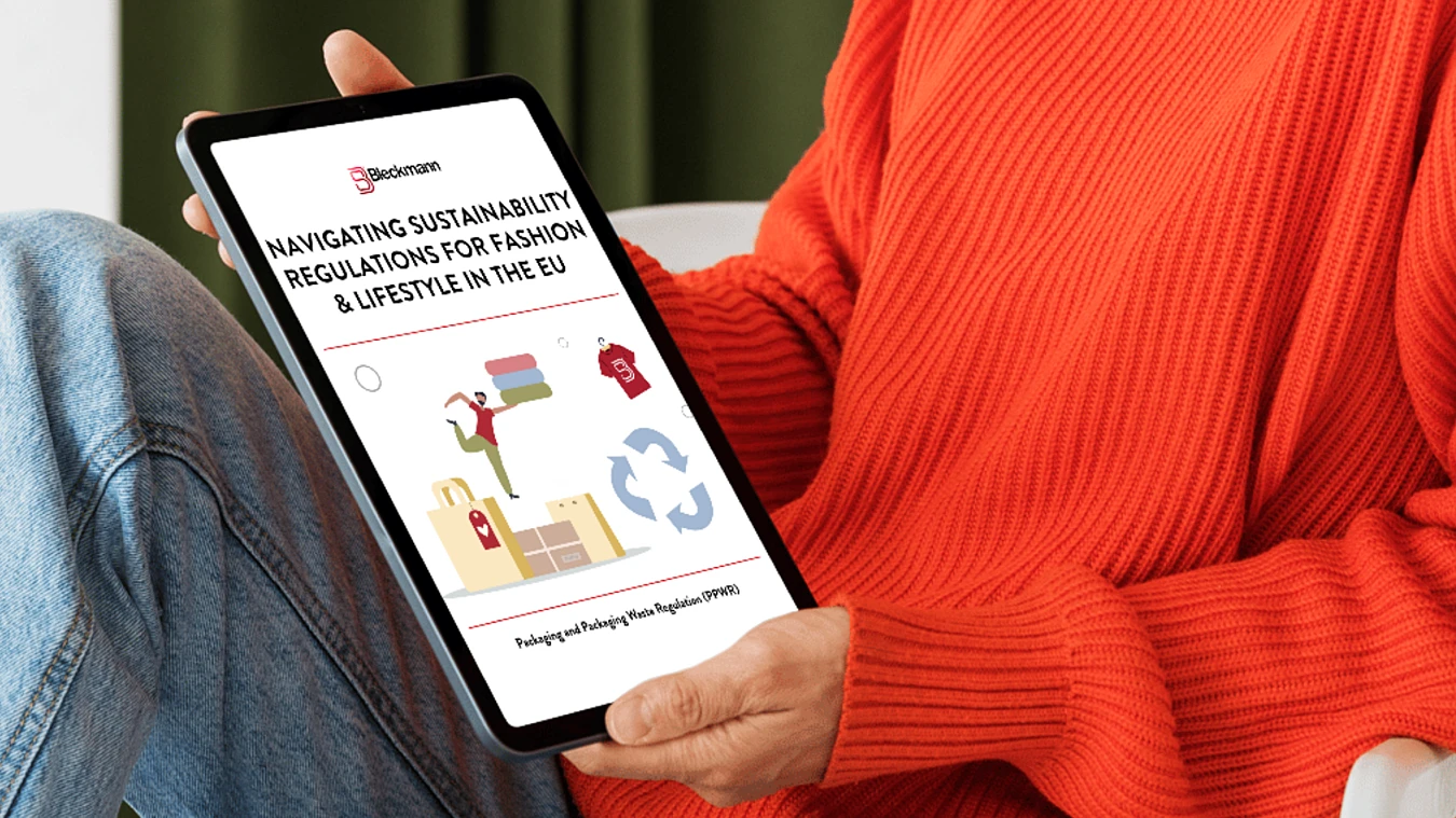 Person holding a tablet displaying a document titled "Navigating Sustainability Regulations for Fashion & Lifestyle in the EU" with icons related to recycling and shopping.