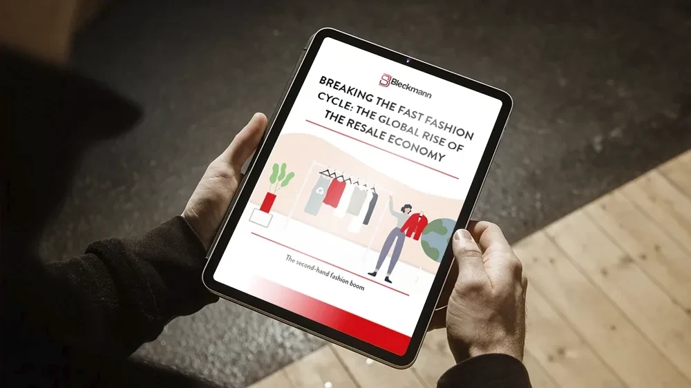 A person holds a tablet displaying a document titled "BREAKING THE FAST FASHION CYCLE: THE GLOBAL RISE OF THE RESALE ECONOMY" with an illustration of clothes and a woman.