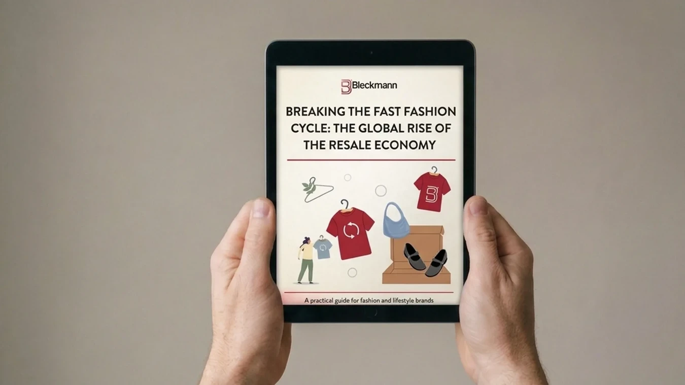 Hands holding a tablet displaying Bleckmann's guide "Breaking the Fast Fashion Cycle: The Global Rise of the Resale Economy," subtitled "A practical guide for fashion and lifestyle brands.