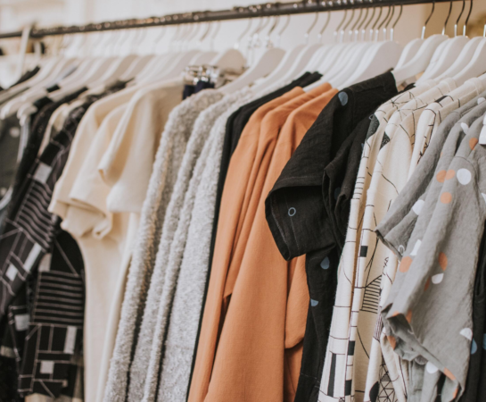 In a well-organized store, a display rack holds an assortment of fashionable clothes, ready for customers to browse.