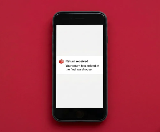 A smartphone displays a message reading, “Return received. Your return has arrived at the final warehouse,” against a red background.