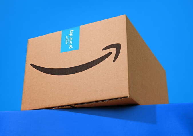 A cardboard Amazon box with a Prime Day label sits on a blue surface against a blue background.