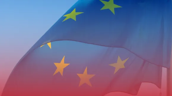 The European Union flag with yellow stars on a blue field waves against a gradient sky.
