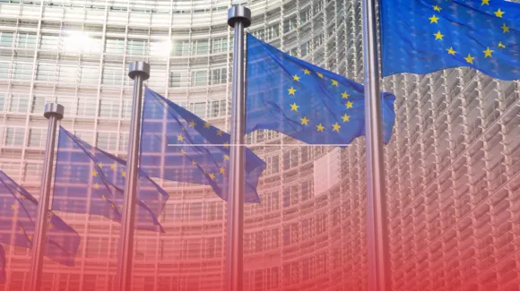 European Union flags waving outside a modern curved glass building.