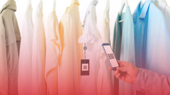 A person scans a QR code with a smartphone near a row of hanging shirts in various pastel colors.