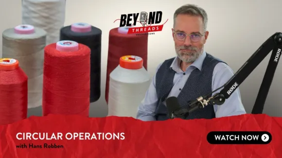 Man seated in front of a microphone, surrounded by large spools of thread. Text reads: "Beyond Threads Productions: Circular Operations with Hans Robben. Watch Now.