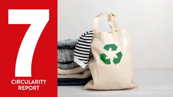 A stack of folded clothes sits next to a tote bag with a recycling symbol; a striped shirt is draped from the bag. A large number 7 with “Circularity Report” is on the left in red.