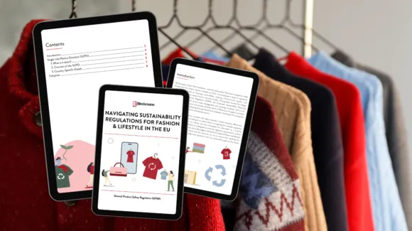 Three tablets displaying pages of an e-book about EU sustainability regulations in fashion and lifestyle are shown in front of a rack of colorful sweaters.
