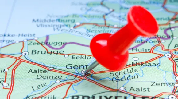 A red pushpin marks the city of Ghent on a detailed map of Belgium, showing surrounding towns, roads, and geographic features.