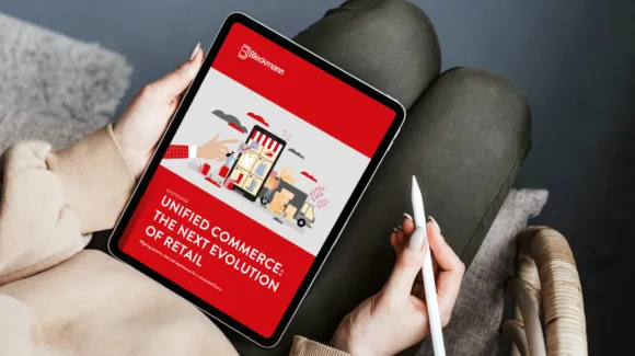 Person holding a tablet displaying a digital report titled "Unified Commerce: The Next Evolution of Retail" with an illustration of a store and delivery vehicles on the cover.