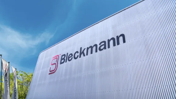 Large white building with the name "Bleckmann" and logo on the exterior, pictured against a blue sky with adjacent branded flags.