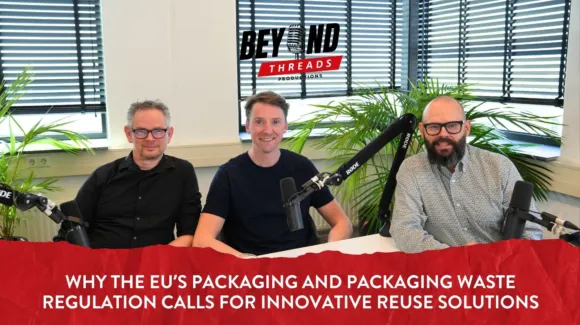 Three men sit at a table with microphones in a studio, with text about EU packaging waste regulation and reuse solutions displayed at the bottom.