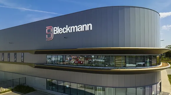 A modern industrial building with the Bleckmann logo on the exterior, featuring large windows and a curved design under a blue sky.