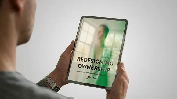 A person holds a tablet displaying a digital magazine or report titled "Redesigning Ownership" with blurred background imagery.