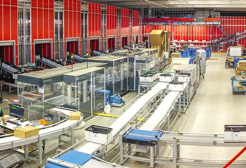 An automated package sorting facility with conveyor belts, sorting stations, and an operator at a computer terminal.