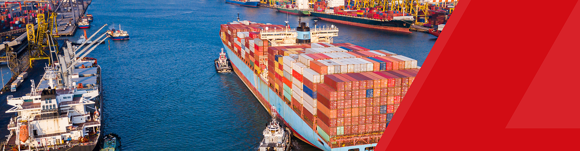 A large cargo ship loaded with shipping containers is escorted by tugboats through a busy industrial port with cranes and other vessels.